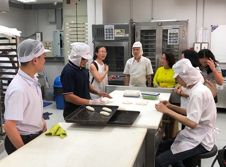 Visitors observing the baking process at the 60+ Plus Bakery & Cafe