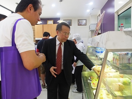 Mr. Piroon showing visitors 60 Plus+ Bakery & Cafe freshly baked products