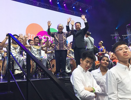 Mr. Piroon and Mr. Tommy with raised hands along with the Thai Wheelchair Dance Team