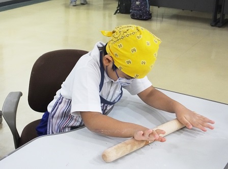 A student using a rolling pin in making bread dough