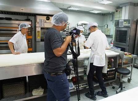 Camera crew taking videos of the 60 Plus+ Bakery & Cafe staff with disabilities in the baking and training area