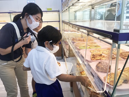 A student selecting bread from the 60 Plus+ Bakery & Cafe rack