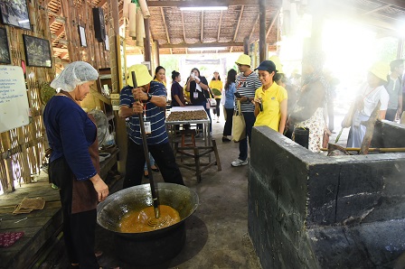 A participant trying out the laborious coconut sugar-making process at Amphawa