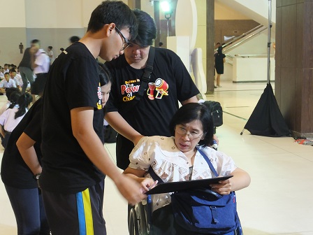Volunteers assist a wheelchair user during registration