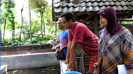 Farmer with Disabilities Feeding Catfish